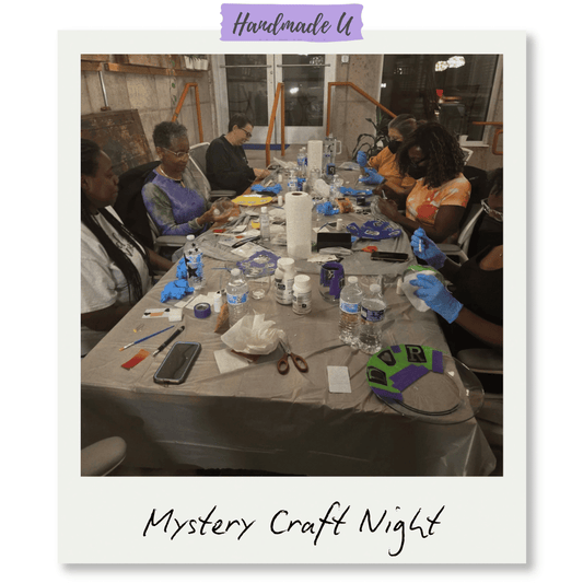 Group of people at a table with supplies, participating in a mystery craft night event.